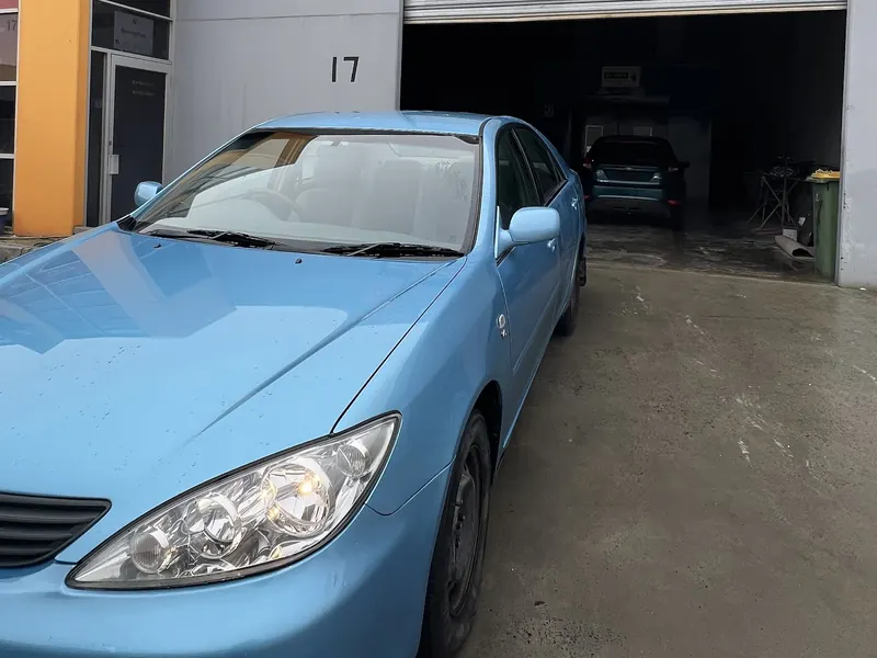 A light blue sedan parked outside the roller door of Factory 17