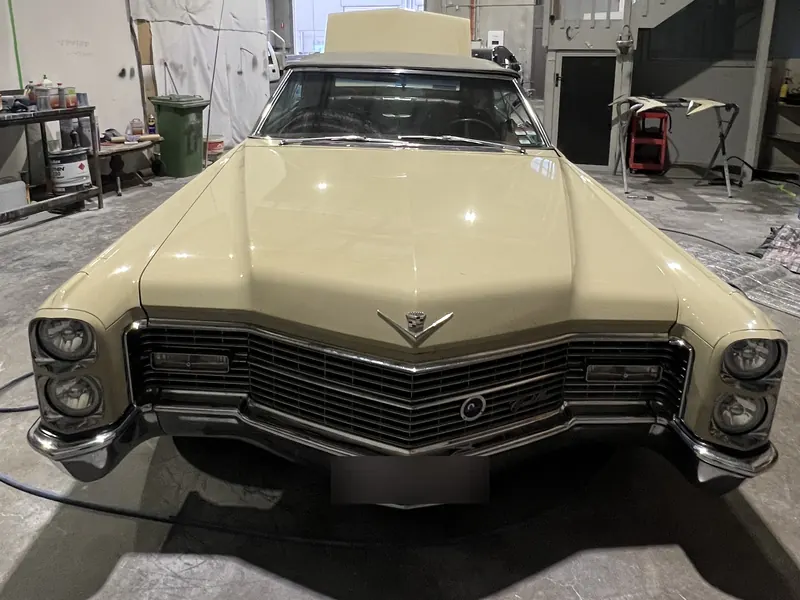 A cream classic convertible in the workshop, seen from the front