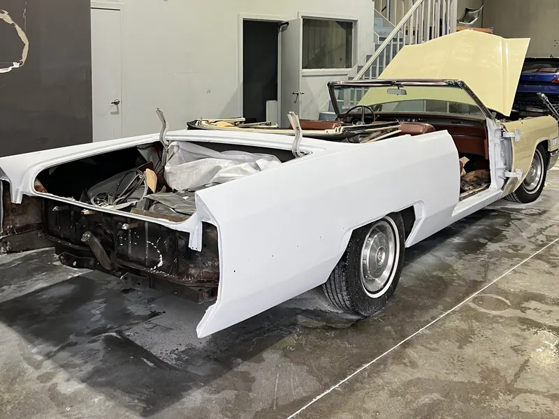 A classic convertible in the workshop with its rear panels in white