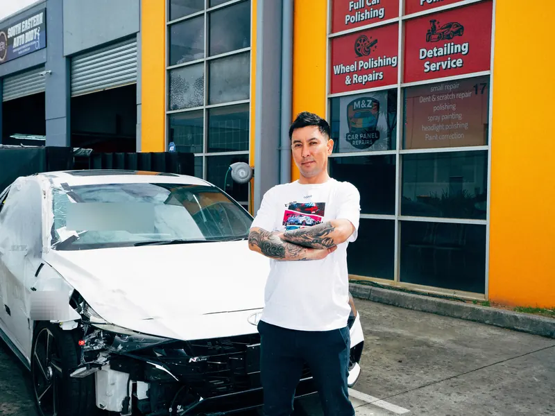 A white sedan with a crushed front end in for repair at the workshop