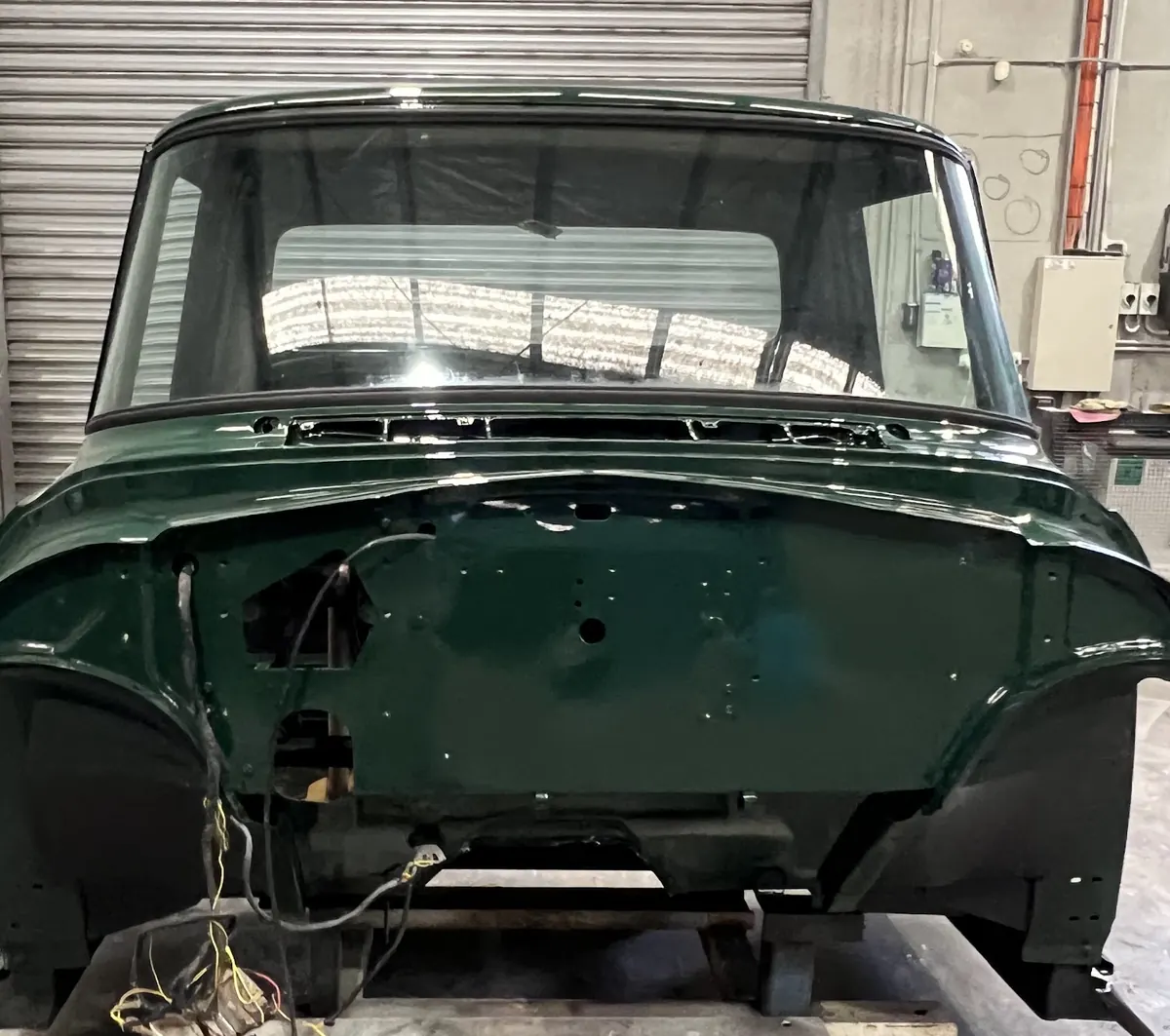 The front of the same truck cab in fresh dark green paint on its stand