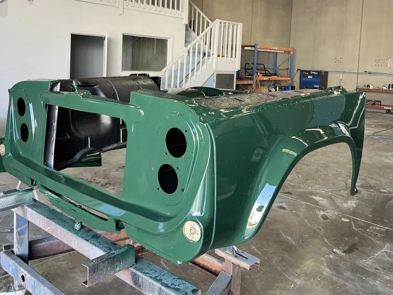 The front panels of a classic truck in fresh green paint on a stand