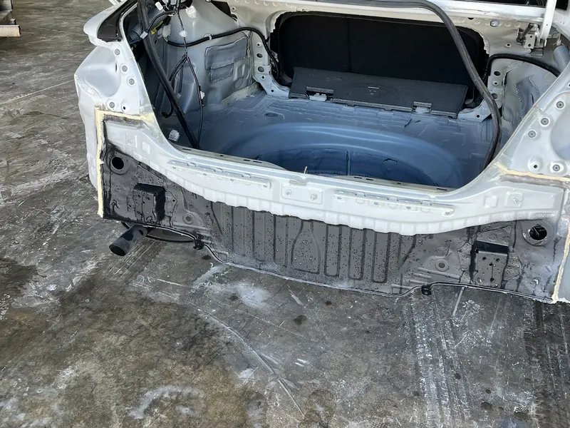 The rear of a white sedan stripped back to the boot floor for repair